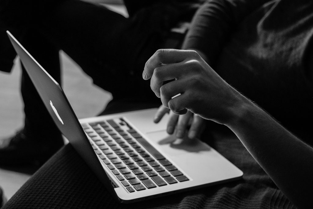 black and white photo of a woman typing on a laptop